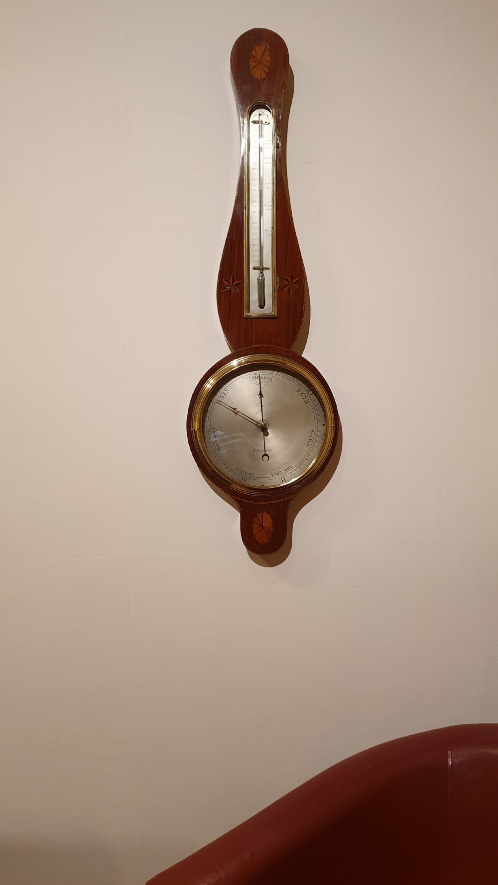An antique mahogany wheel barometer featuring a banjo-shaped wooden casing with an upper vertical thermometer scale and a lower circular dial. View III
