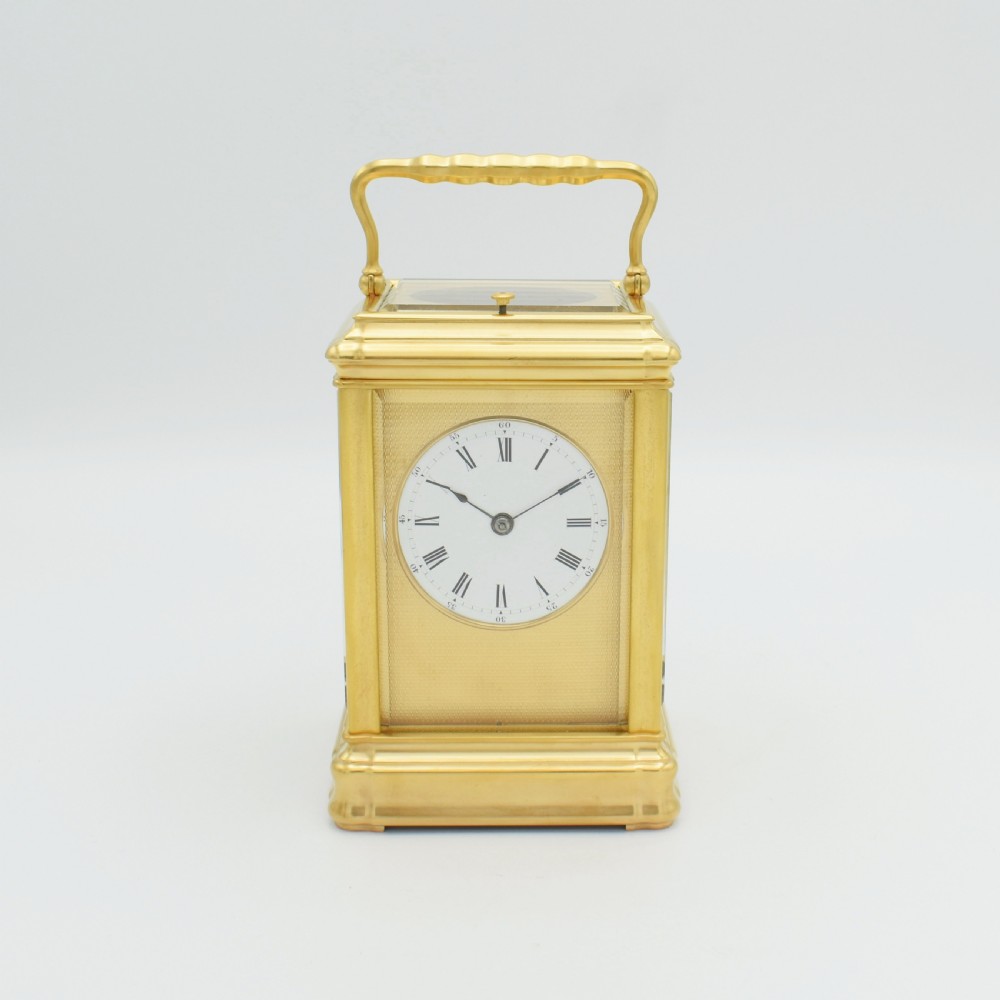A nineteenth-century French gilt brass carriage clock featuring a rectangular case with glass panels, a top carrying handle, and a white enamel dial with Roman numerals.