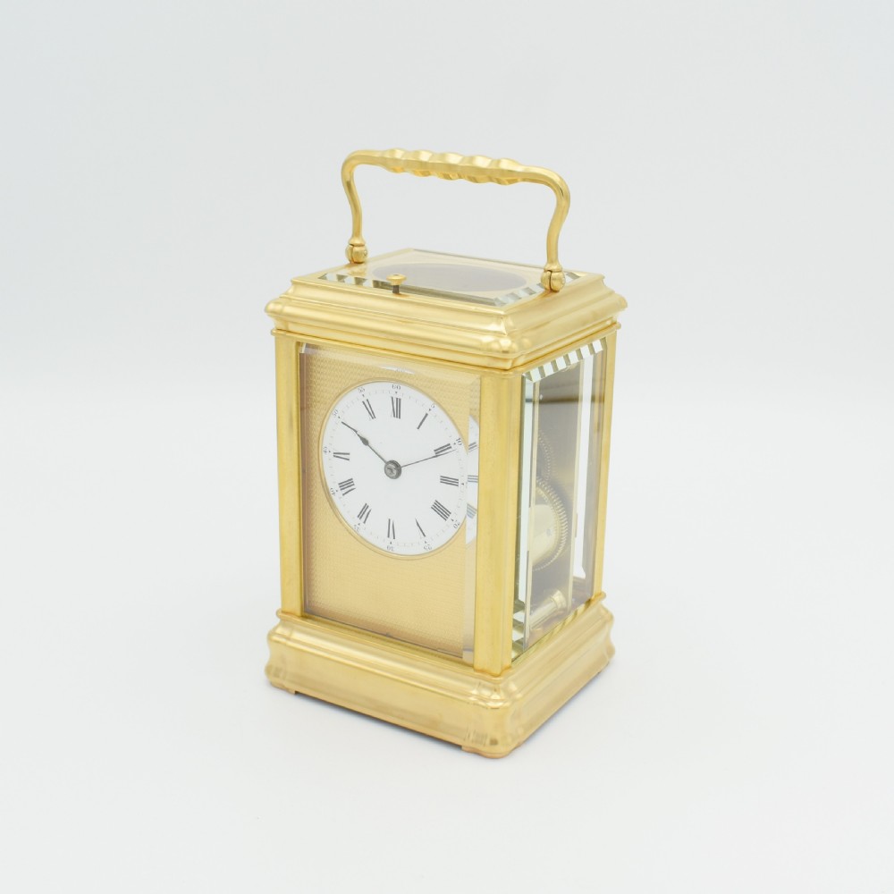 A nineteenth-century French gilt brass carriage clock featuring a rectangular case with glass panels, a top carrying handle, and a white enamel dial with Roman numerals. View II