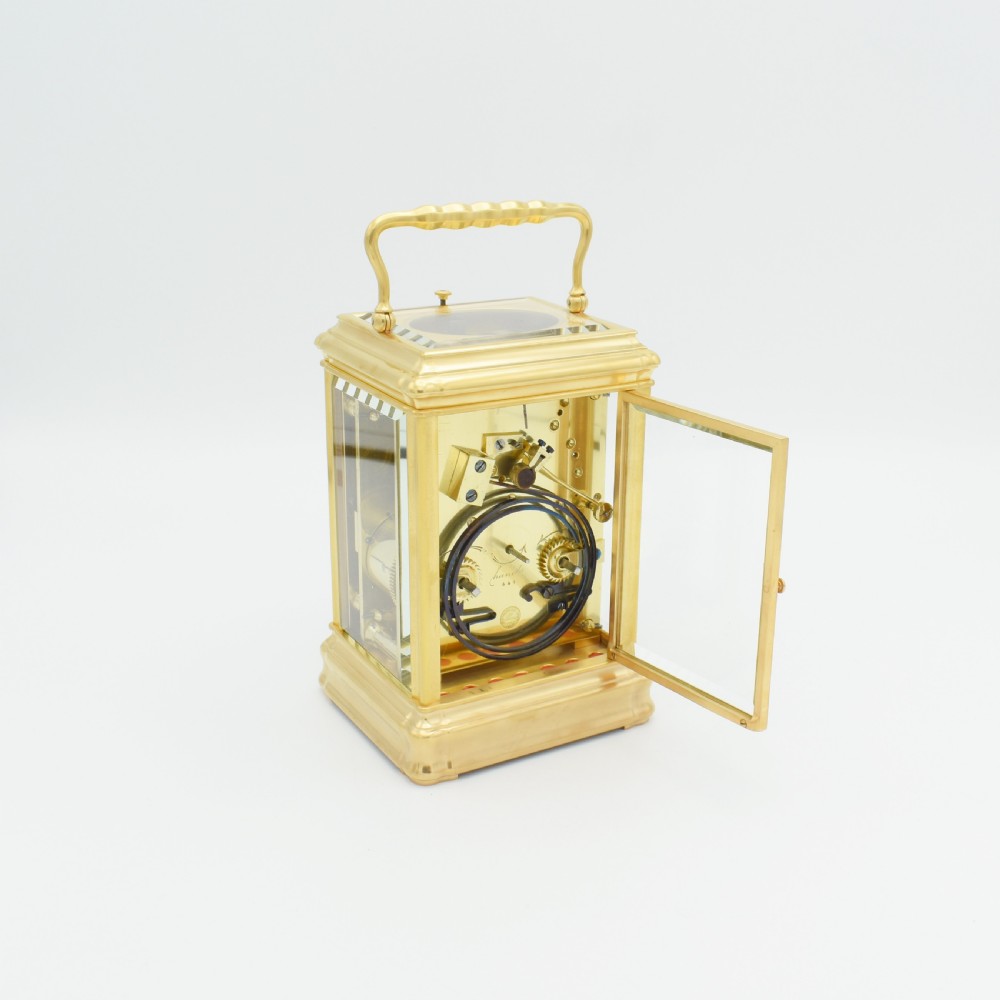 A nineteenth-century French gilt brass carriage clock featuring a rectangular case with glass panels, a top carrying handle, and a white enamel dial with Roman numerals. View III