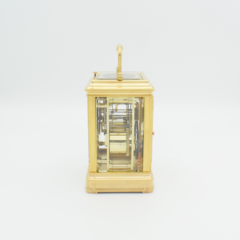 A nineteenth-century French gilt brass carriage clock featuring a rectangular case with glass panels, a top carrying handle, and a white enamel dial with Roman numerals. View V