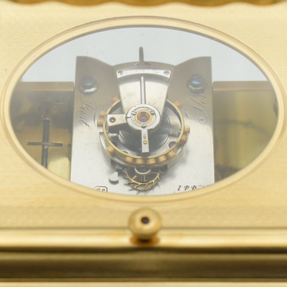 A nineteenth-century French gilt brass carriage clock featuring a rectangular case with glass panels, a top carrying handle, and a white enamel dial with Roman numerals. View VII