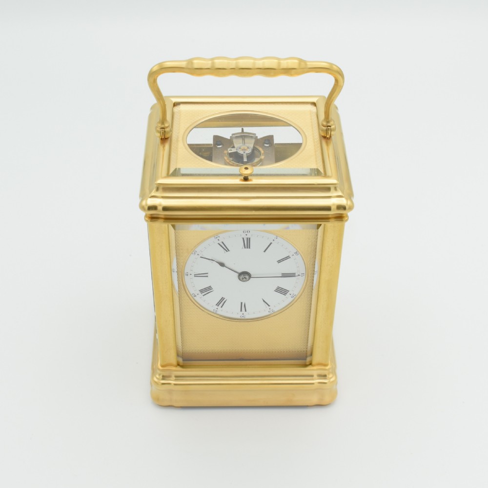 A nineteenth-century French gilt brass carriage clock featuring a rectangular case with glass panels, a top carrying handle, and a white enamel dial with Roman numerals. View VIII