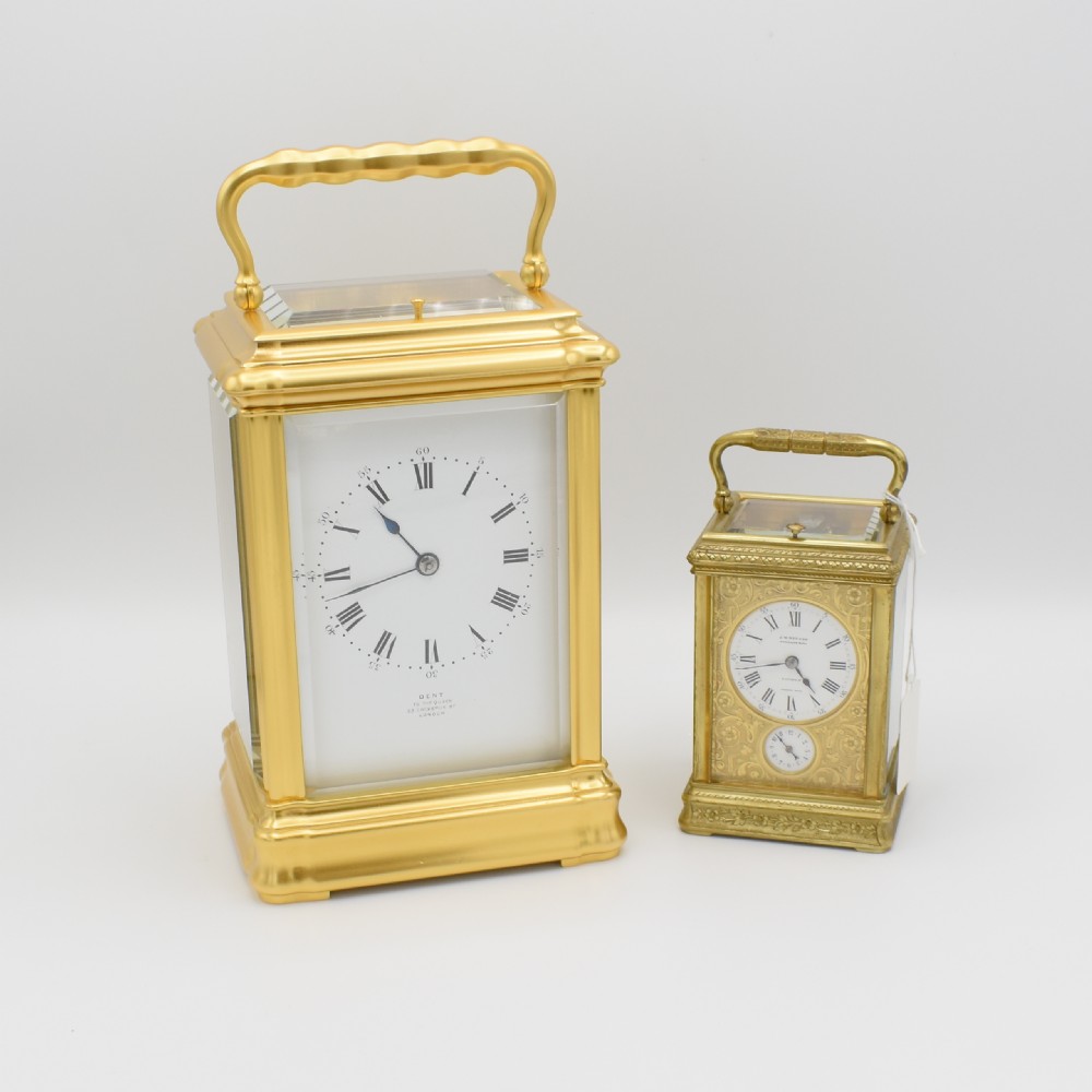 A gilded brass carriage clock featuring a shaped top carrying handle, clear bevelled glass panels, and a white enamel dial with Roman numerals. View IX