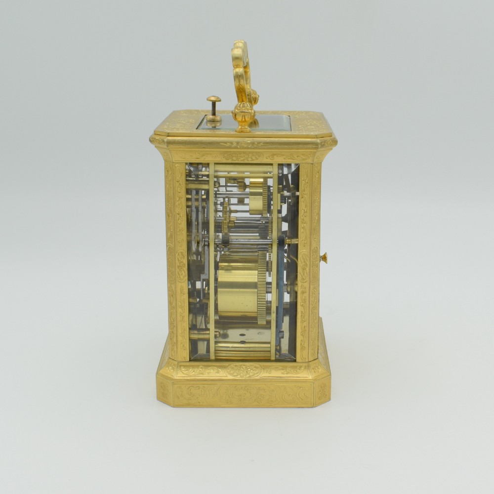 An antique gilded brass carriage clock with an ornate handle, detailed chasing on the case, and a white enamel dial. View II