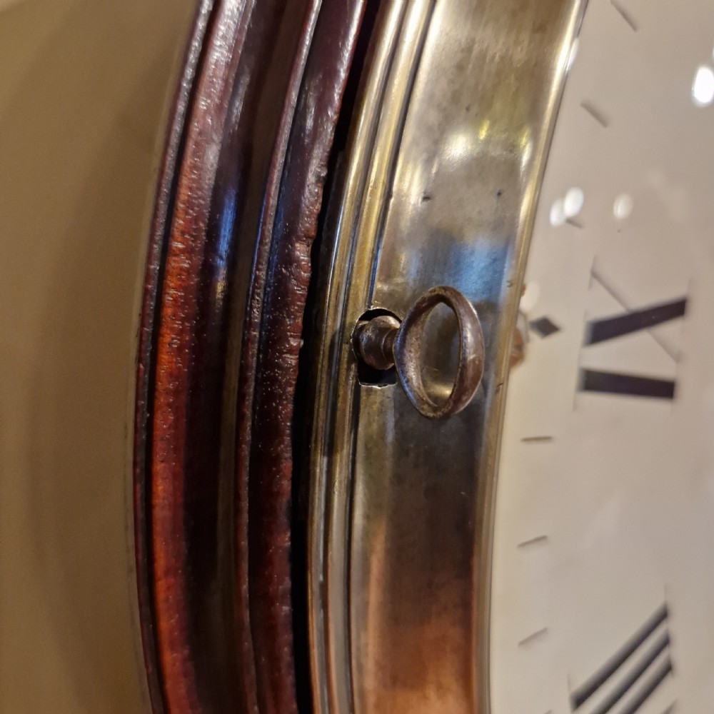 An antique circular fusee wall clock featuring a dark mahogany surround, brass bezel, and a white dial with Roman numerals signed Richd Clark Newport. View VI