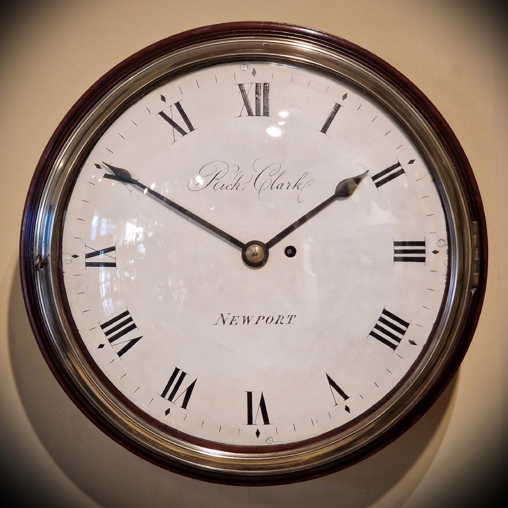 An antique circular fusee wall clock featuring a dark mahogany surround, brass bezel, and a white dial with Roman numerals signed Richd Clark Newport.