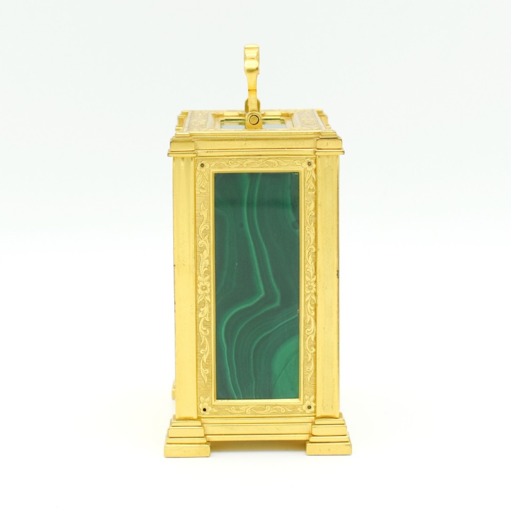 A rectangular gilt brass antique carriage clock featuring fine scroll engraving, malachite stone inlays, and a white dial with Roman numerals. View VI