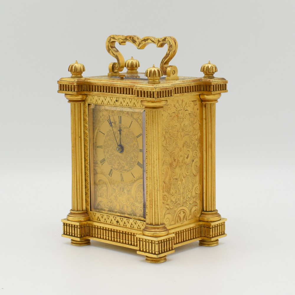 An ornate gilt brass repeating carriage clock featuring fluted corner columns alongside its original leather transport case and key. View VI