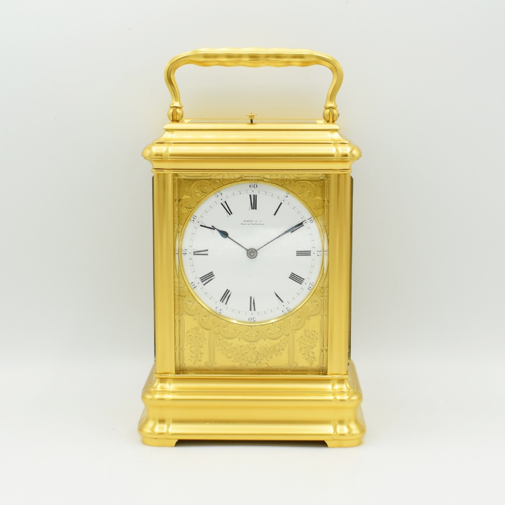 An antique gilt brass carriage clock with an engraved face and white enamel dial housed inside a fitted dark brown leather travelling case with a handle. View III