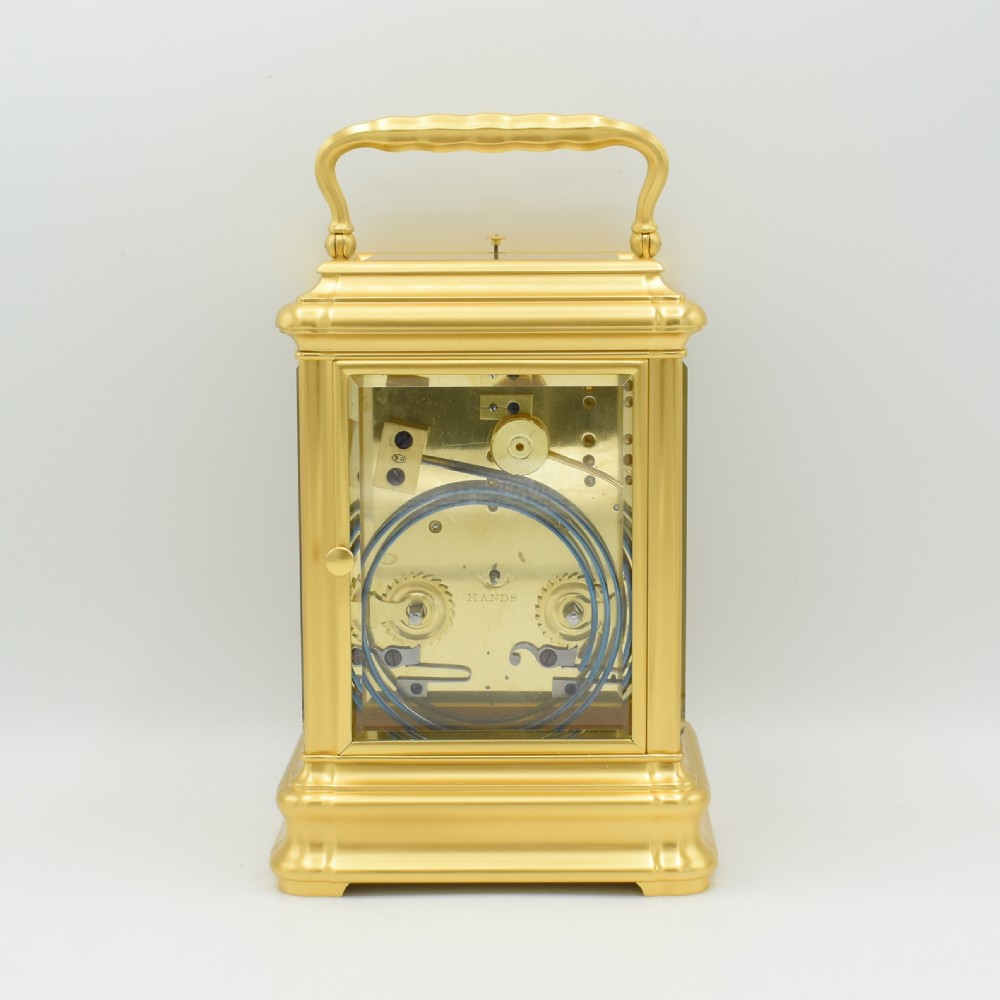An antique gilt brass carriage clock with an engraved face and white enamel dial housed inside a fitted dark brown leather travelling case with a handle. View VI