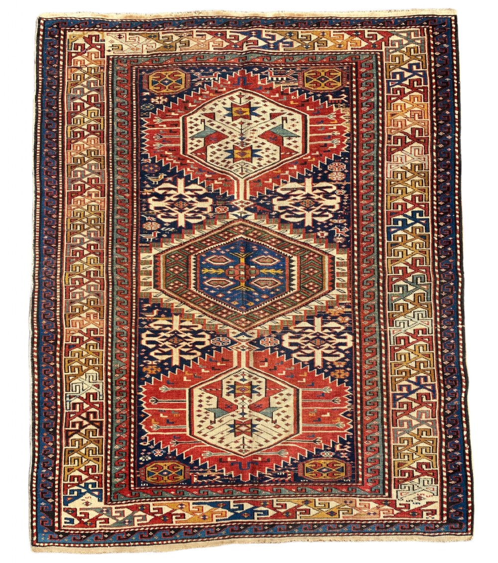 An antique hand-knotted Caucasian Shirvan wool rug featuring central geometric diamond medallions and intricate layered borders in red, cream, and navy blue.