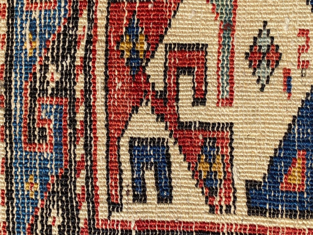 An antique hand-knotted Caucasian Shirvan wool rug featuring central geometric diamond medallions and intricate layered borders in red, cream, and navy blue. View XI