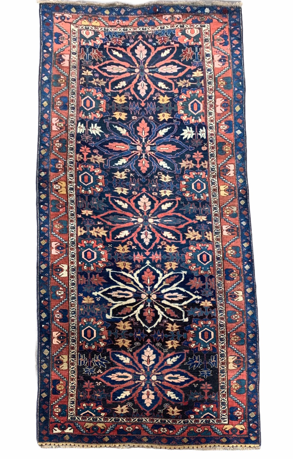 An antique hand-knotted Persian Bidjar long rug featuring a central column of large star rosettes on a navy blue field enclosed within a decorated terracotta border.