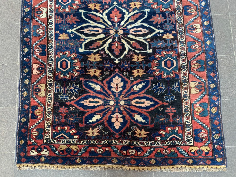 An antique hand-knotted Persian Bidjar long rug featuring a central column of large star rosettes on a navy blue field enclosed within a decorated terracotta border. View II