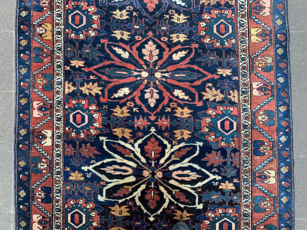 An antique hand-knotted Persian Bidjar long rug featuring a central column of large star rosettes on a navy blue field enclosed within a decorated terracotta border. View III