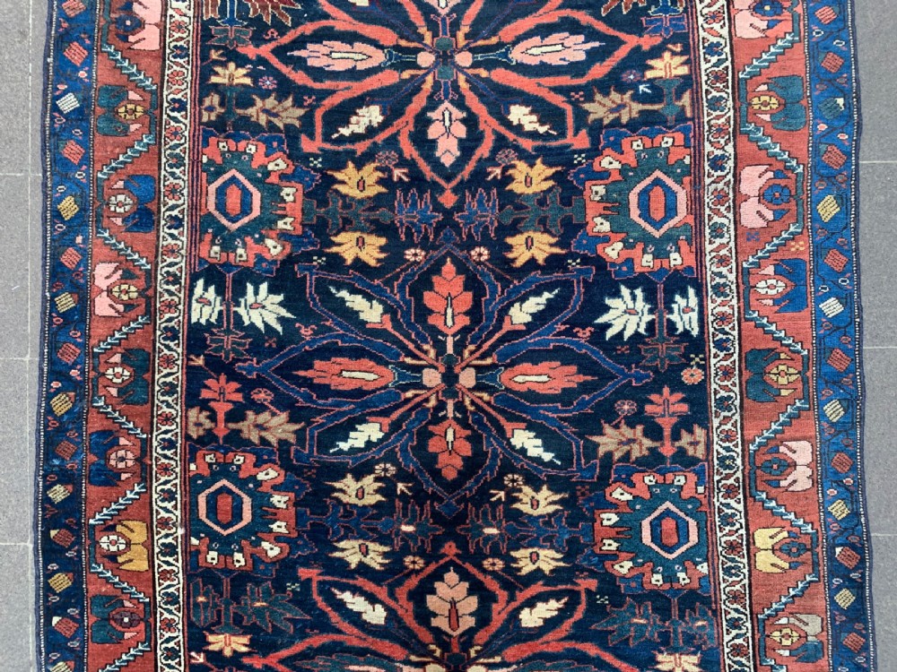 An antique hand-knotted Persian Bidjar long rug featuring a central column of large star rosettes on a navy blue field enclosed within a decorated terracotta border. View IV