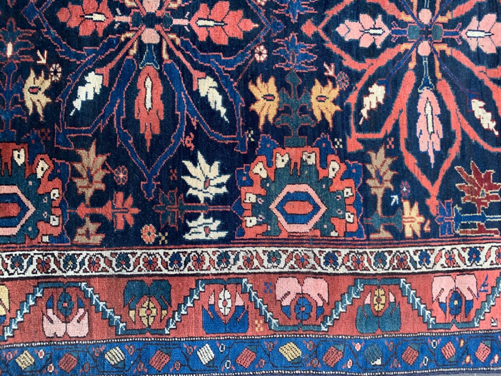 An antique hand-knotted Persian Bidjar long rug featuring a central column of large star rosettes on a navy blue field enclosed within a decorated terracotta border. View VI