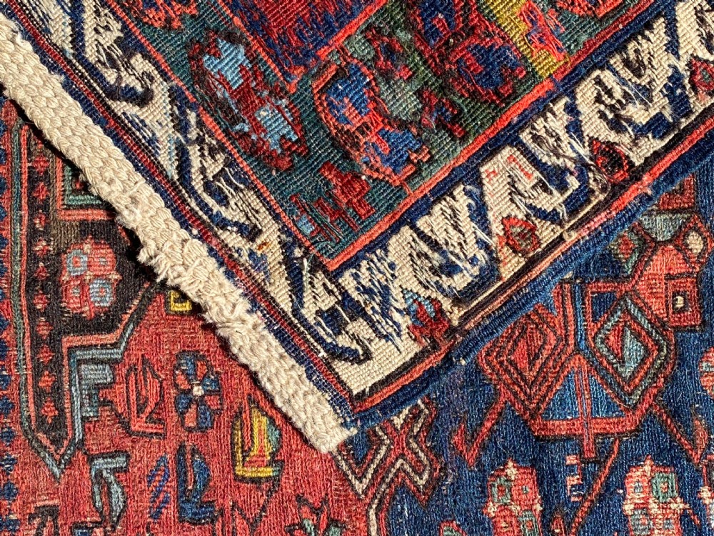 An antique Caucasian Soumak wool rug featuring geometric stepped medallions on a terracotta red field with blue and multi-coloured borders. View XI