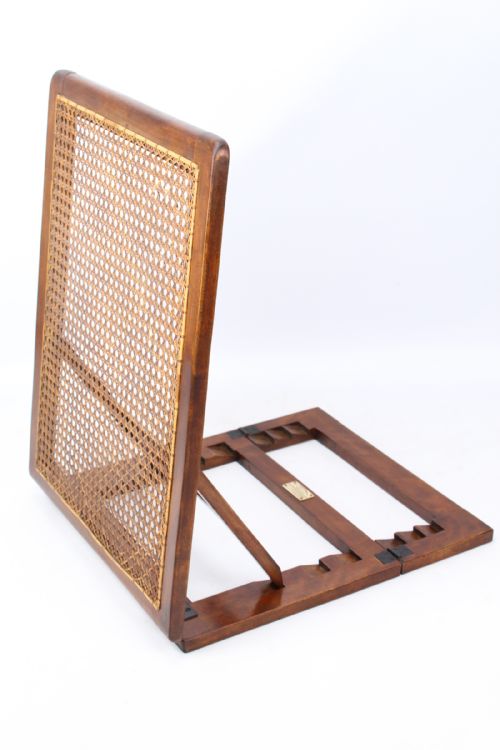 fig 1. An Edwardian adjustable folding campaign backrest crafted from dark mahogany wood with a woven cane panel resting on a ratcheted frame.