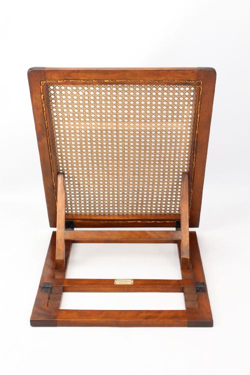 fig 2. An Edwardian adjustable folding campaign backrest crafted from dark mahogany wood with a woven cane panel resting on a ratcheted frame.