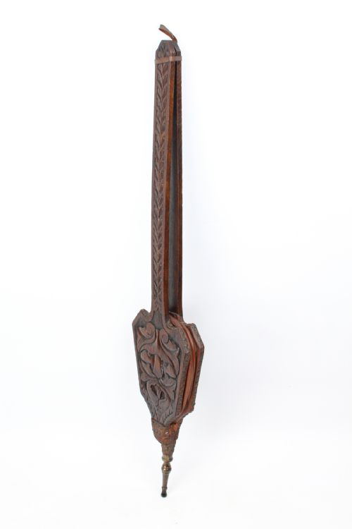 fig 1. A long-handled dark oak fire bellows decorated with carved foliage motifs, leather siding, brass studs, and a brass nozzle.