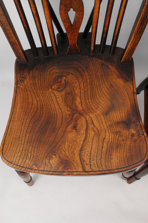 fig 1. A near pair of antique dark timber Windsor kitchen chairs featuring pierced wheelback splats, contoured saddle seats, and turned legs.