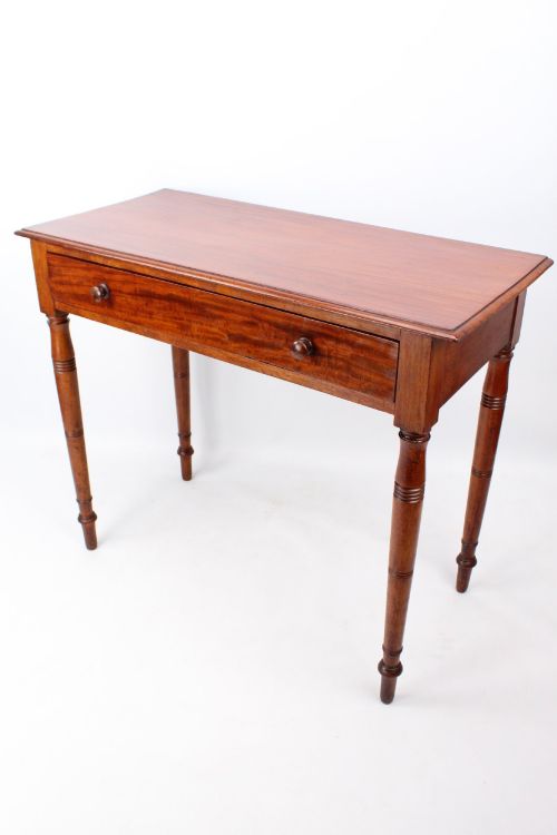fig 1. A Victorian mahogany writing table featuring a long frieze drawer with two turned wooden knobs, elevated on four ring-turned tapered legs.