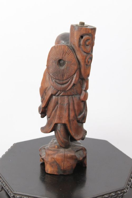 fig 2. A hand-carved dark wood figure of the Daoist Immortal Liu Hai holding a three-legged toad, set upon a carved rockwork base with a brass lamp fitting at the top.