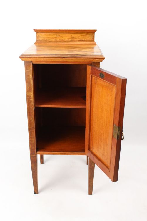 fig 1. An Edwardian burr walnut bedside cabinet featuring a small gallery top, crossbanded inlaid door panel, drop brass handle, and square tapered legs.