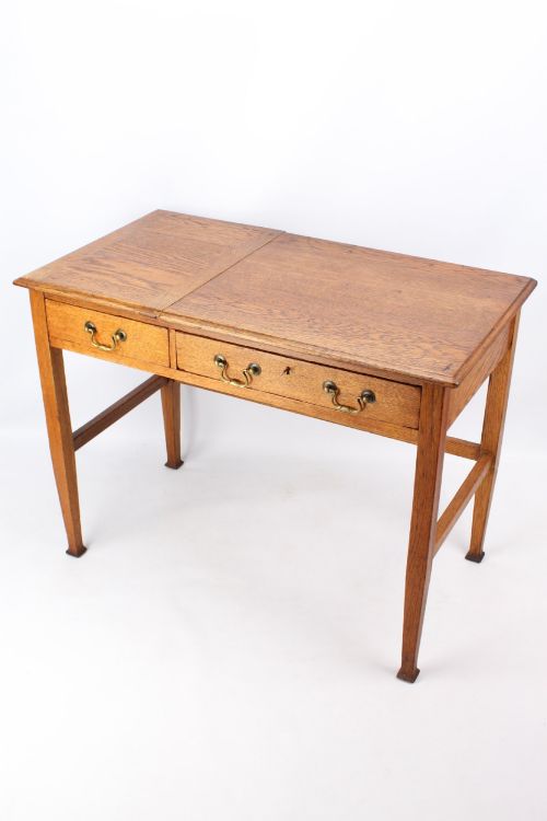 fig 1. A late Victorian Arts and Crafts oak writing desk featuring drawers with brass swan-neck handles and tapered square legs.