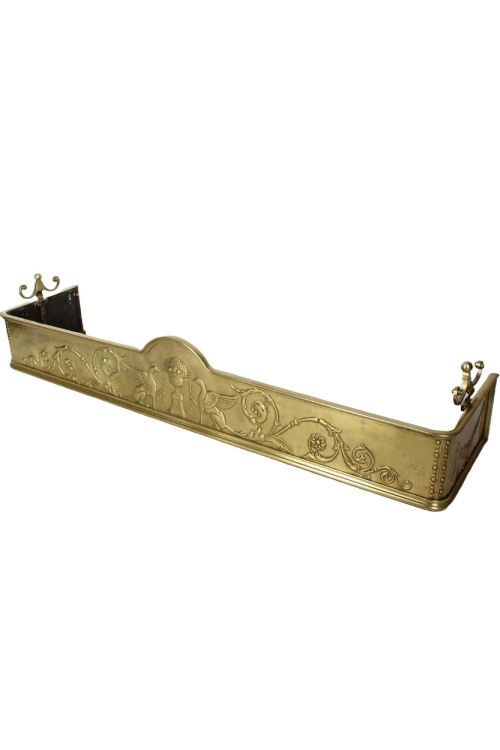 fig 1. A long Victorian brass fireplace fender featuring embossed Neoclassical relief decoration of central urns, winged sphinxes, and foliate scrolls.