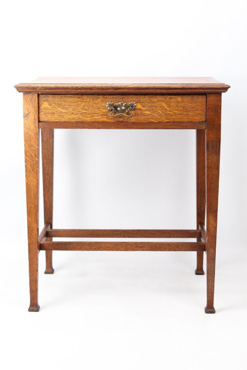 fig 1. A compact Arts and Crafts oak writing desk featuring a single drawer with a brass drop handle, straight square legs, and lower stretchers.