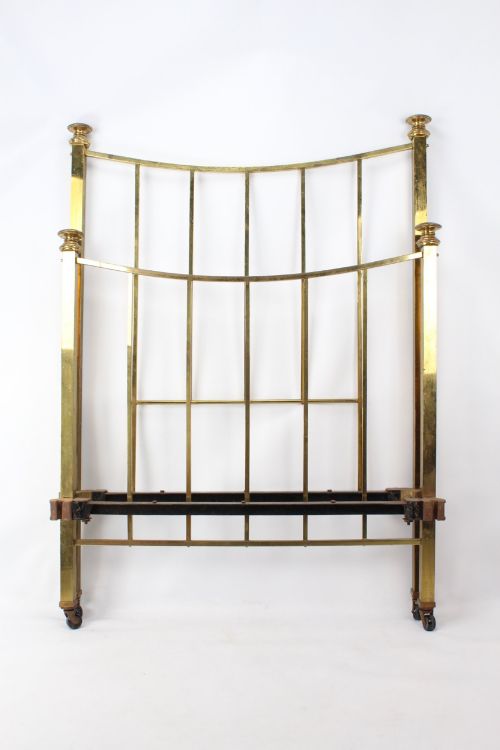 fig 1. A Victorian brass single bed frame featuring a gently curved top rail, vertical spindles, turned finials, and original wheel castors.