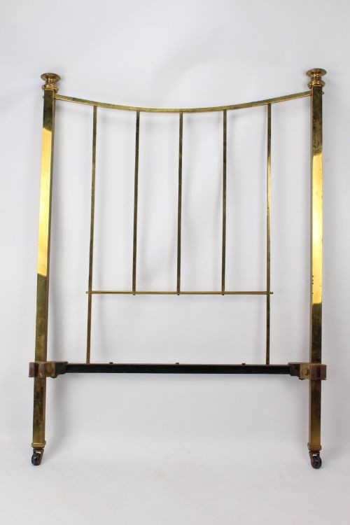 fig 2. A Victorian brass single bed frame featuring a gently curved top rail, vertical spindles, turned finials, and original wheel castors.