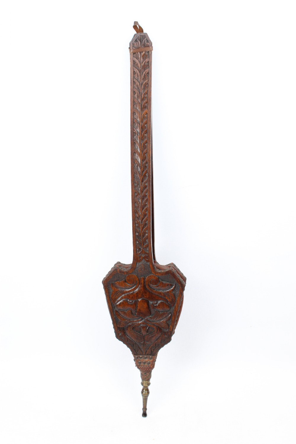 A long-handled dark oak fire bellows decorated with carved foliage motifs, leather siding, brass studs, and a brass nozzle.