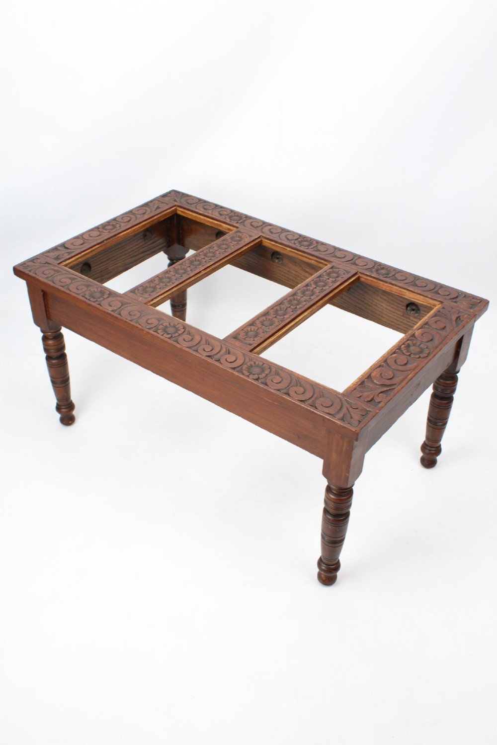 An Edwardian carved oak luggage stand with relief floral carving along the open top frame and turned wooden legs. View II