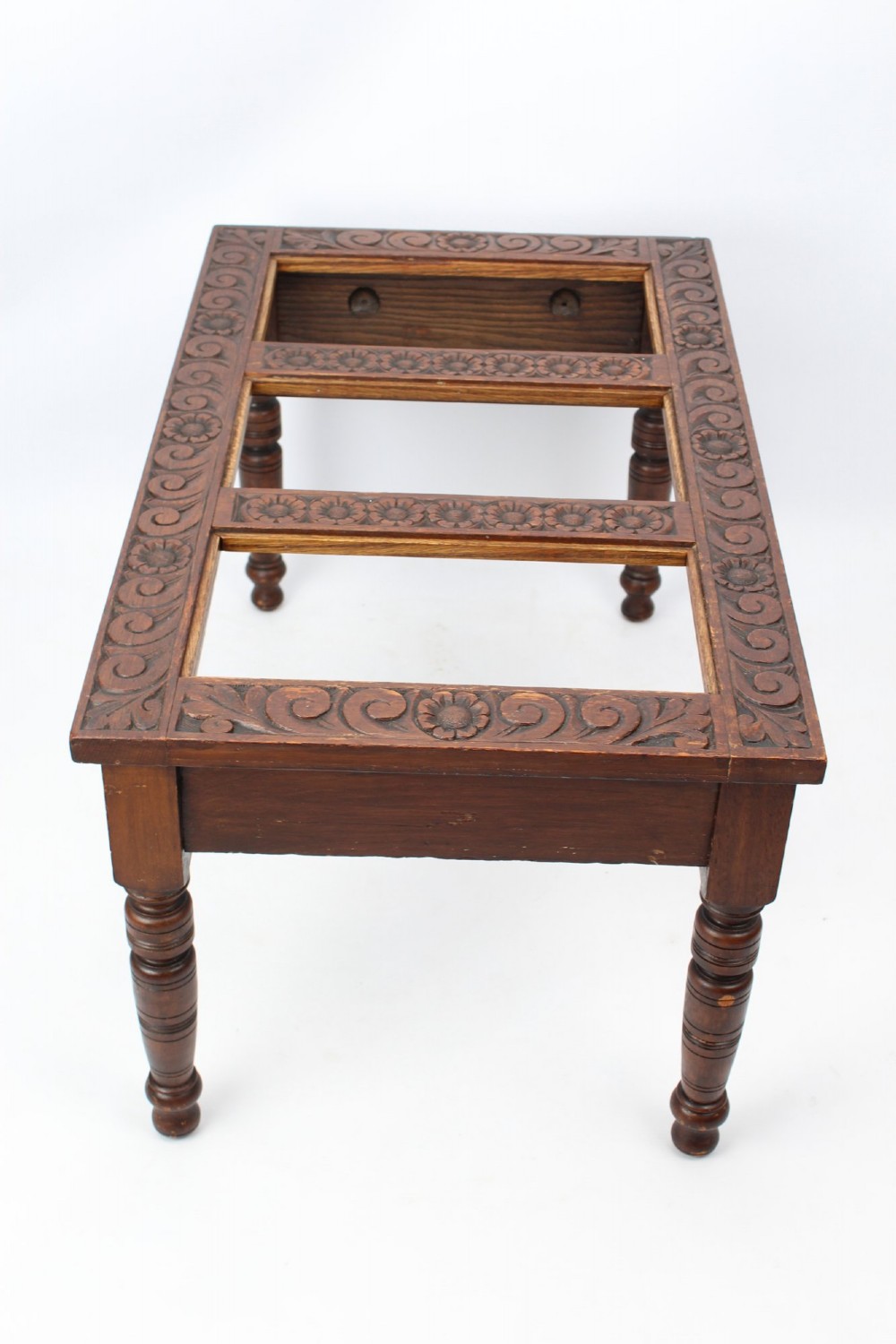 An Edwardian carved oak luggage stand with relief floral carving along the open top frame and turned wooden legs. View III