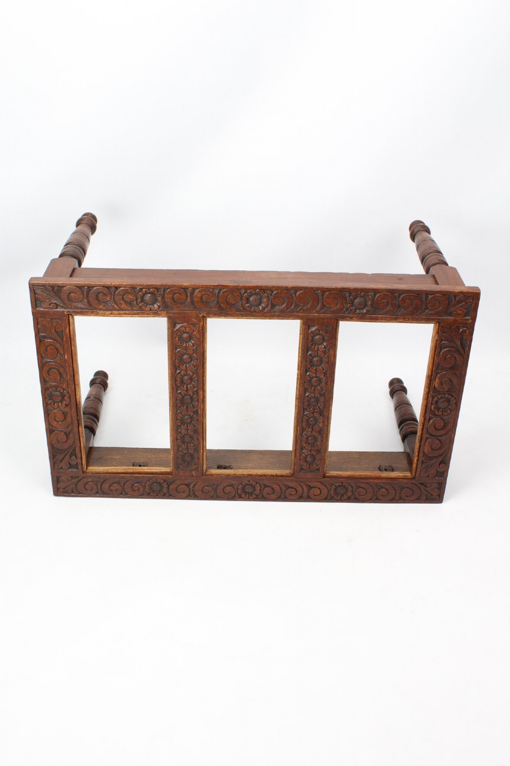 An Edwardian carved oak luggage stand with relief floral carving along the open top frame and turned wooden legs. View IV