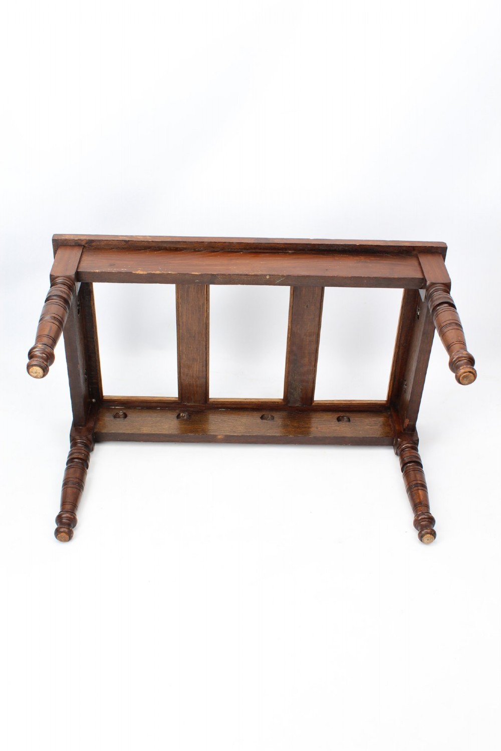 An Edwardian carved oak luggage stand with relief floral carving along the open top frame and turned wooden legs. View V