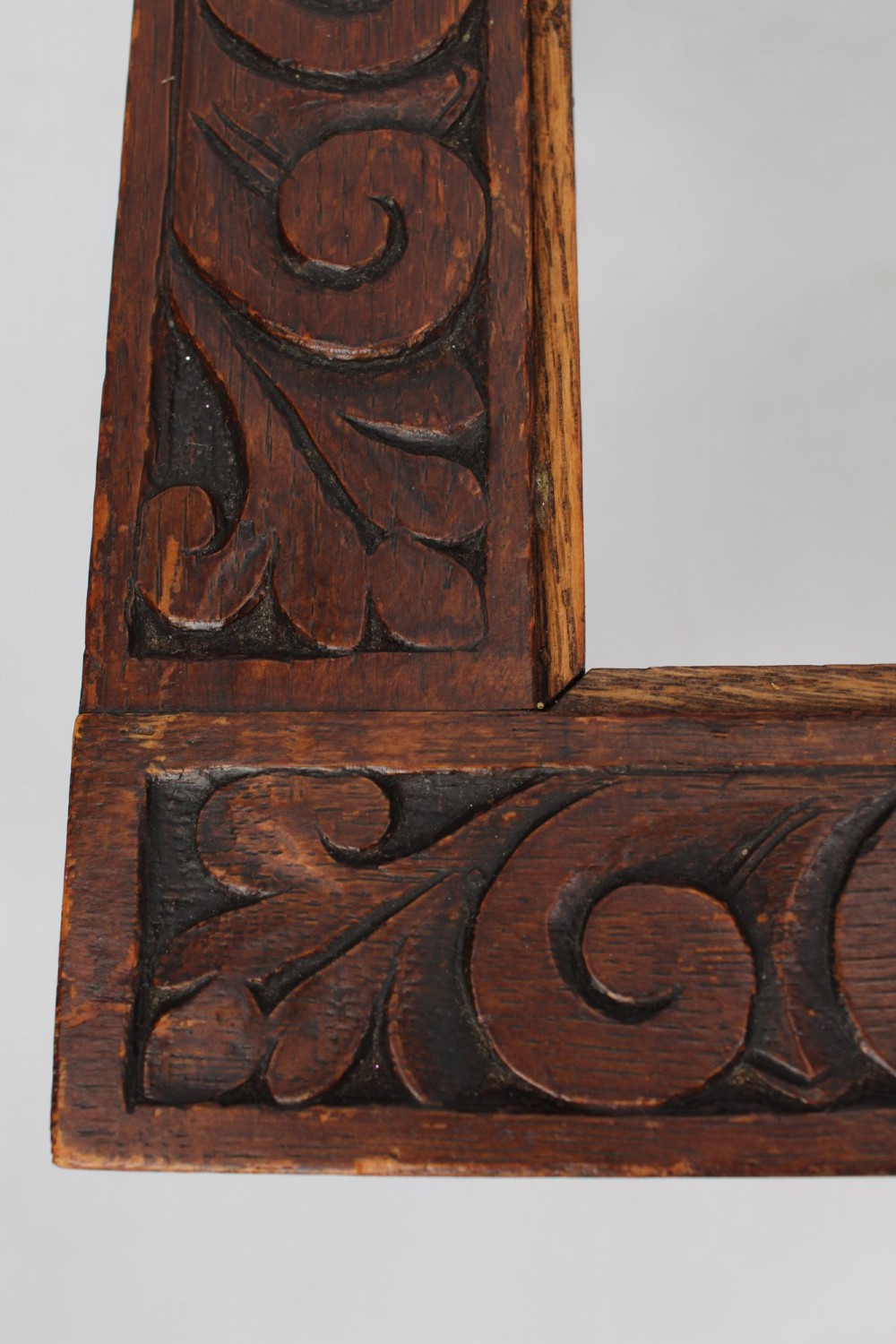 An Edwardian carved oak luggage stand with relief floral carving along the open top frame and turned wooden legs. View VI