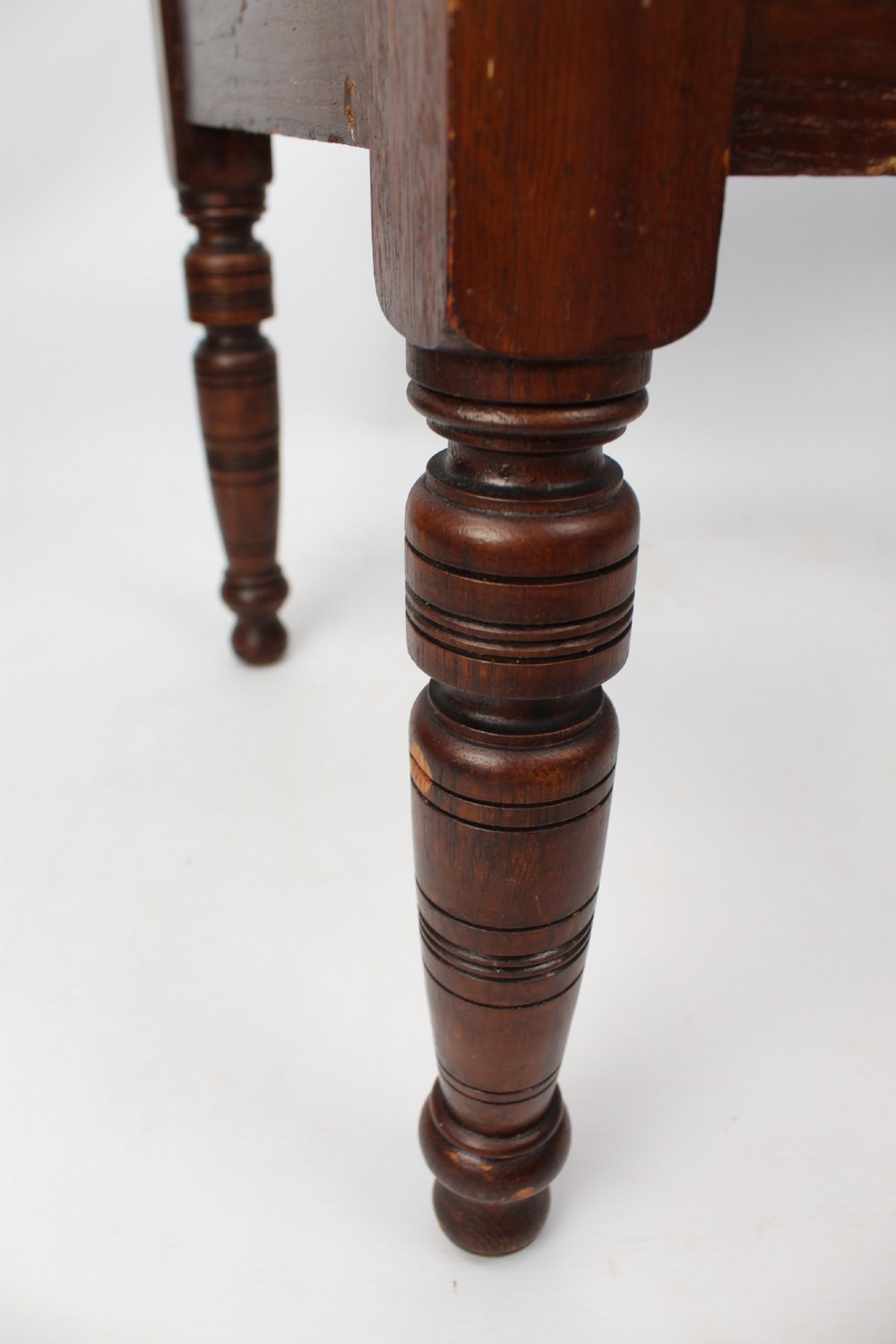 An Edwardian carved oak luggage stand with relief floral carving along the open top frame and turned wooden legs. View IX