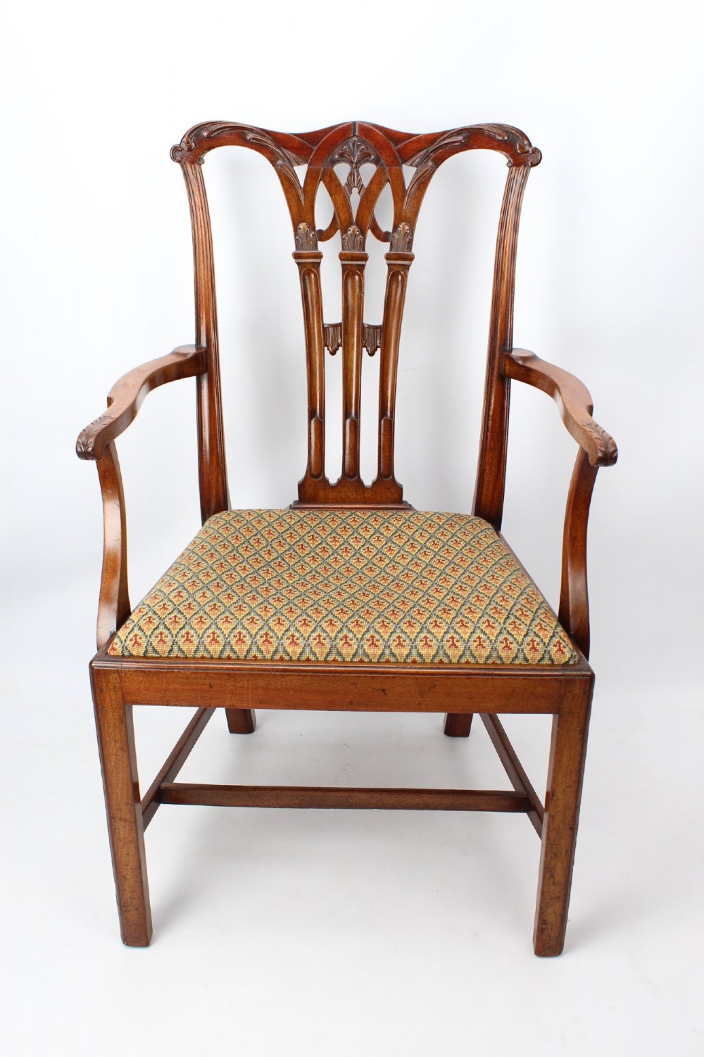 An Edwardian Chippendale style mahogany desk chair with a pierced carved back splat, curved armrests, and a patterned tapestry seat.