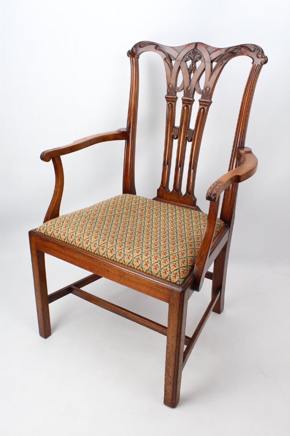An Edwardian Chippendale style mahogany desk chair with a pierced carved back splat, curved armrests, and a patterned tapestry seat. View II