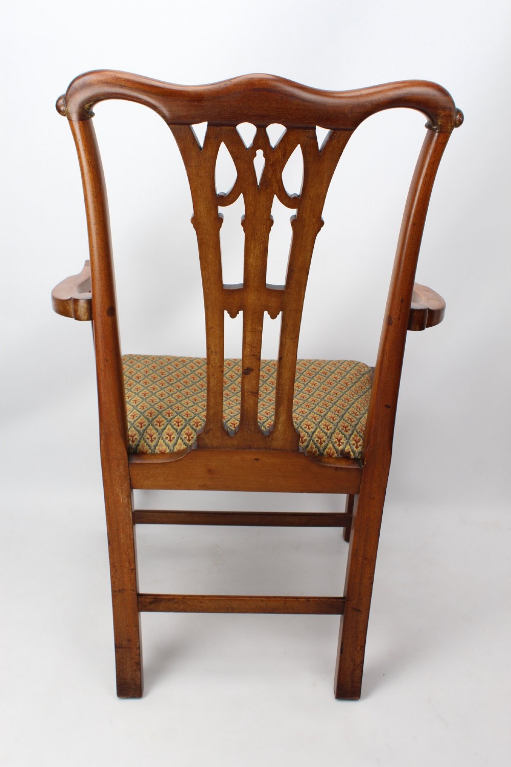 An Edwardian Chippendale style mahogany desk chair with a pierced carved back splat, curved armrests, and a patterned tapestry seat. View IV