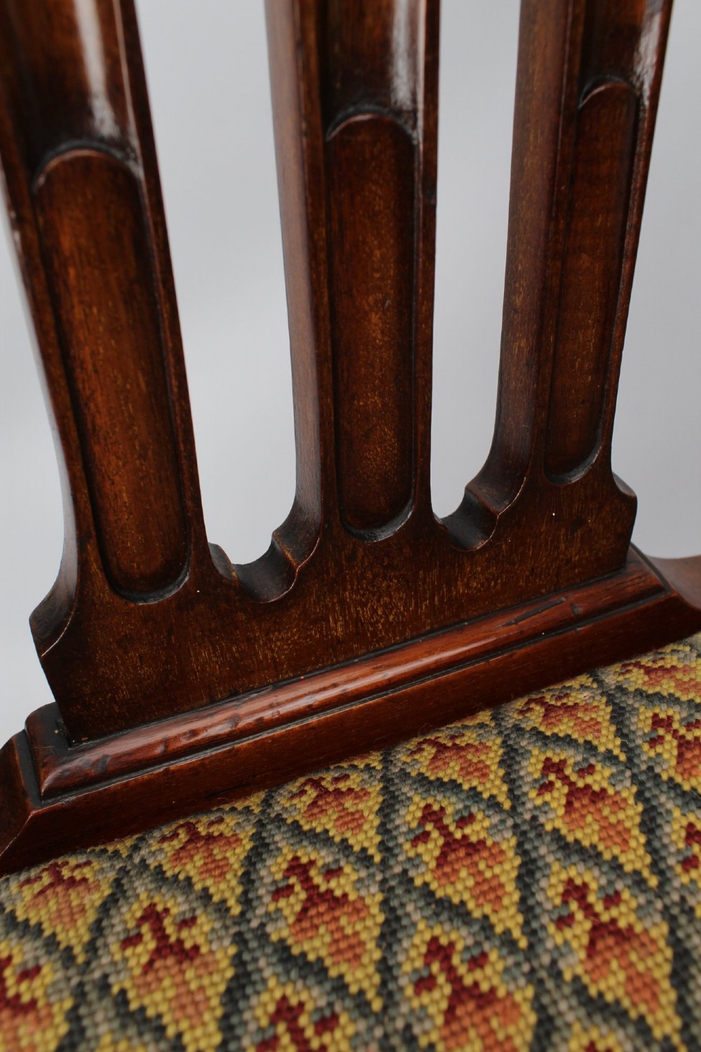 An Edwardian Chippendale style mahogany desk chair with a pierced carved back splat, curved armrests, and a patterned tapestry seat. View VIII