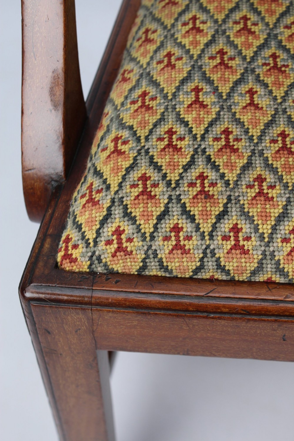 An Edwardian Chippendale style mahogany desk chair with a pierced carved back splat, curved armrests, and a patterned tapestry seat. View X