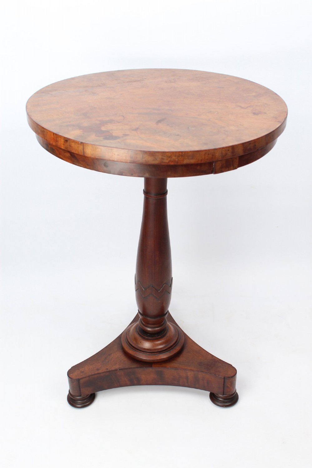 A circular mahogany wine table from the William IV period featuring a turned central column on a triform base with flattened bun feet. View II