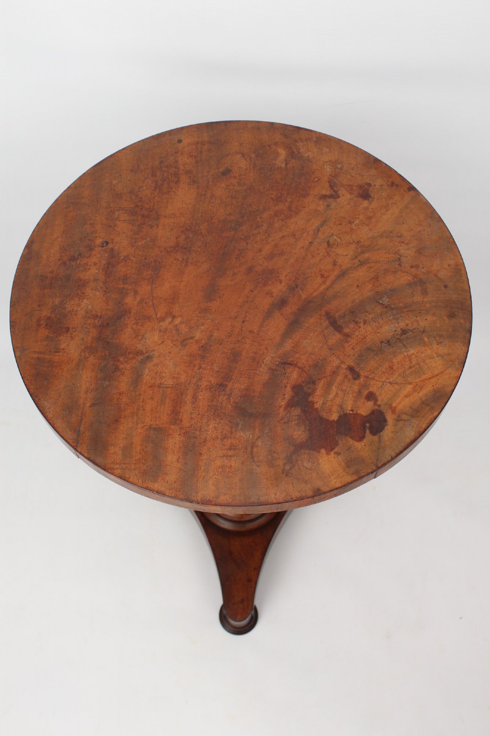 A circular mahogany wine table from the William IV period featuring a turned central column on a triform base with flattened bun feet. View IV