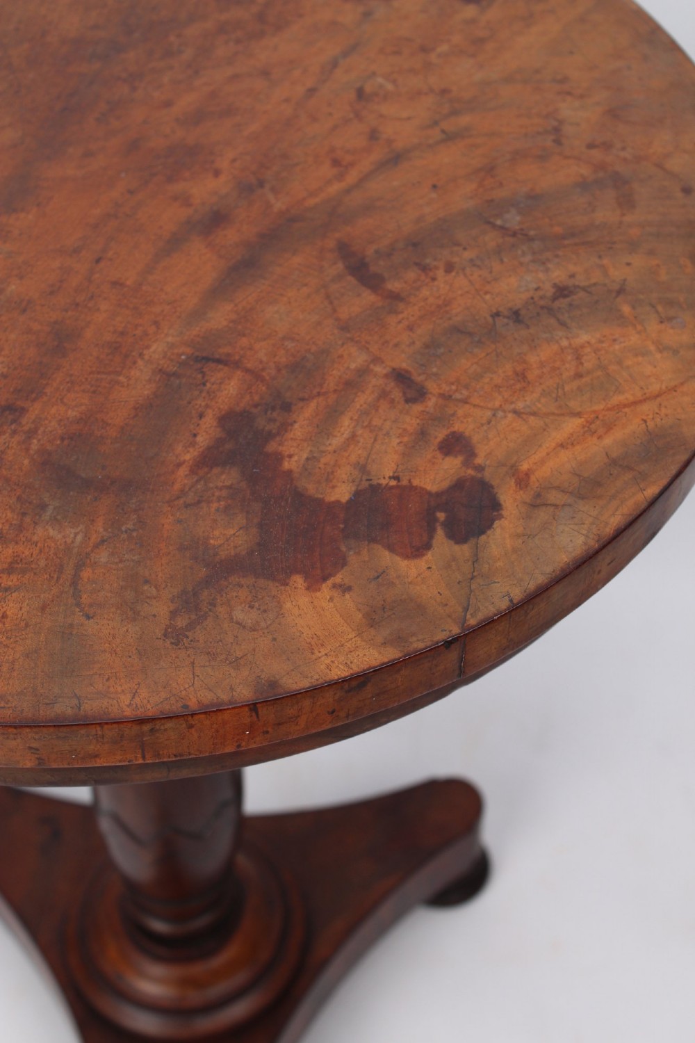 A circular mahogany wine table from the William IV period featuring a turned central column on a triform base with flattened bun feet. View V